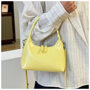 Detailed shot of the buttery yellow leather dumpling bag featuring the embossed brand logo