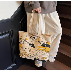 Detail of large canvas tote bag featuring an all-over cartoon cat print with shoulder straps