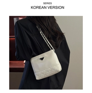 Detail of cream bucket bag showing quilted diamond pattern and gold chain strap