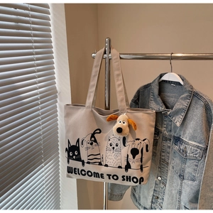 Detail of beige canvas tote bag with cartoon cat dog print and plush puppy charm