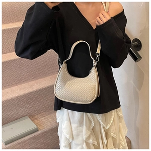 Detailed view of cream crescent bag with woven texture and adjustable shoulder strap