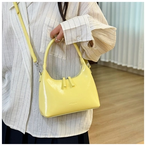 Close-up of yellow oil wax leather dumpling bag with silver zippers and shoulder strap