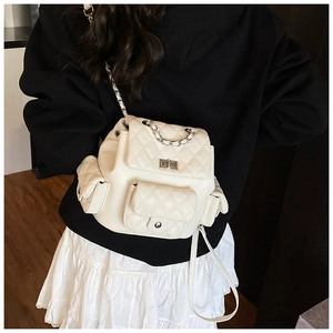 Side view of white quilted mini backpack with silver metal turn lock and chain straps