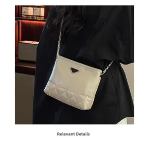 Close-up of quilted beige leather bag with metal triangle plaque and chain strap detail