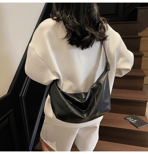 Detail of black crescent crossbody bag with knotted strap and textured leather finish