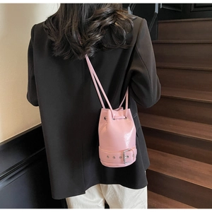 Détail du sac seau rose à cordon avec ceinture décorative porté par un mannequin