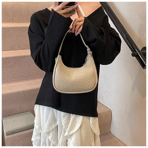 Detailed view of beige hobo bag with crocodile texture worn by a model on stairs