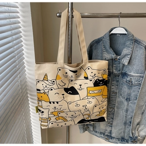 Detail of cute cartoon cat print on a cream canvas tote bag with reinforced handles