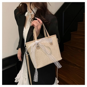Detailed close-up of woven straw handbag with a white lace bow and leather handles