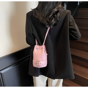 Détail du sac seau rose brillant avec boucle décorative et fermeture par cordon serrage