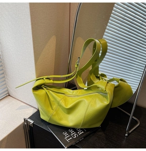 Detail of neon green pleated shoulder bag with adjustable strap and smooth zipper closure