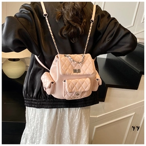 Pink quilted backpack with silver chain straps shown on model in cozy interior