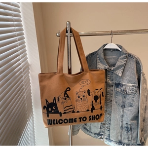Detail of cartoon animal prints and Welcome to Shop text on large brown canvas tote bag