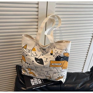 Detail of canvas tote bag featuring cute hand-drawn cartoon cat pattern on black leather sofa