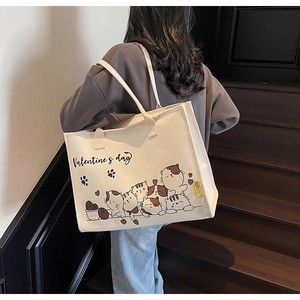 Detail einer Canvas-Tragetasche mit Comic-Katzen-Print, an der Schulter getragen