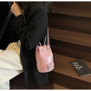 Sac seau en cuir ciré rose avec fermeture à cordon sur un escalier en bois