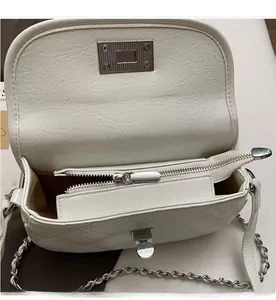 Close-up of internal zipper compartment and silver chain on white quilted bag