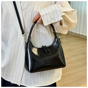 Detail of black glossy crescent bag showing dual zippers and silver hardware finish