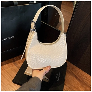 Detail of cream-white woven hobo bag showing fine texture and silver metal hardware