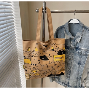 Close-up of khaki canvas tote bag featuring an all-over cute cartoon cat pattern