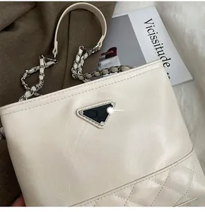 Detailed close-up of ivory bucket bag featuring quilted leather and iconic metal logo