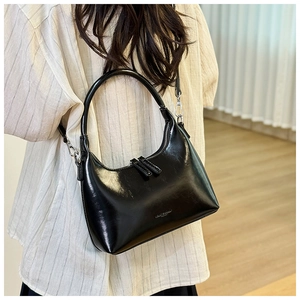 Rear view of a black glossy crescent shoulder bag with metallic strap details