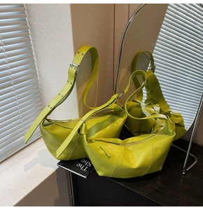Detail of neon lime crescent shoulder bag showing textured faux leather and eyelet strap