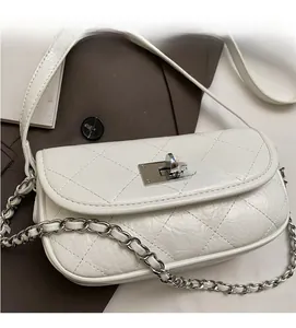 Detailed view of white quilted bag with silver metal chain strap and twist lock closure