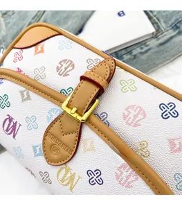Close-up of logo print on white leather bag with brown trim and gold buckle detail