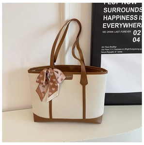Détail de la texture tissée et des finitions en cuir marron sur un grand sac fourre-tout