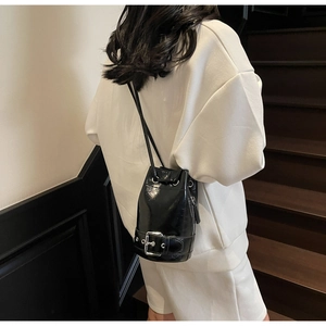 Détail du sac seau noir brillant avec cordon de serrage et boucle de ceinture métal