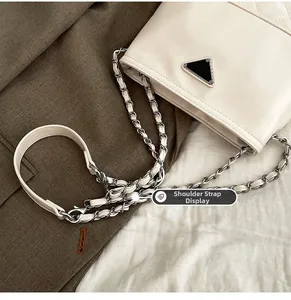 Detail of metal chain and leather shoulder strap on a cream large capacity bucket bag