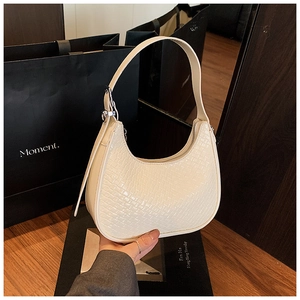 Detail of cream woven textured hobo bag with adjustable silver buckle and leather handle