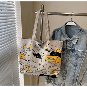 Detail of canvas tote bag featuring cute cartoon cat patterns hanging with denim jacket
