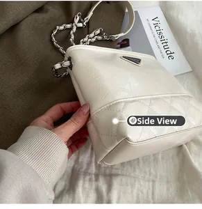 Detailed side view of beige bucket bag with quilted leather texture and chain strap