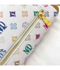 Macro view of a colorful monogram pattern and gold metal zipper on a white leather bag