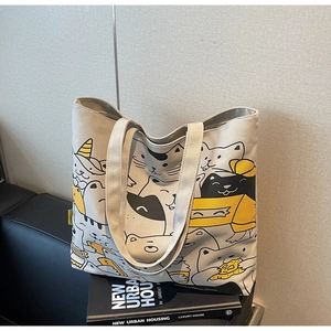 Detail of canvas tote bag with cartoon cat pattern placed on a black sofa