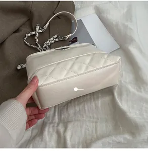 Detail view of the flat bottom on a white quilted chain bucket bag with silver hardware