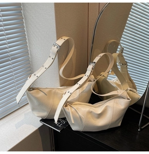 Detail of cream leather crescent bag with silver eyelets and smooth zipper tassel