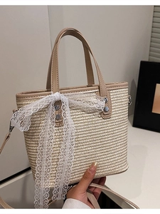 Handwoven straw crossbody bag with beige leather trim and white lace bow decoration