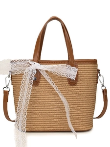 Straw woven tote handbag with brown leather trim and white lace ribbon for beach vacation