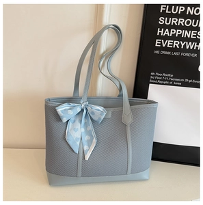 Détail d'un sac cabas en maille bleu clair avec bordure en cuir et foulard en soie imprimé