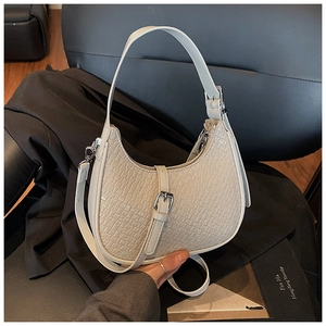Detail of cream crescent bag featuring crocodile texture and silver hardware accents