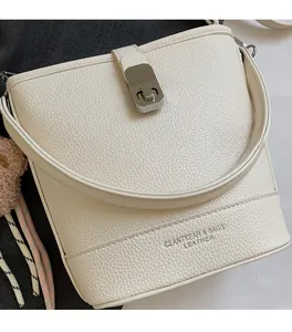 Gros plan détaillé du sac seau en cuir crème avec fermoir en métal argenté et grain cuir