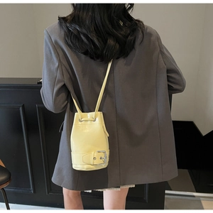 Détail d'un sac seau jaune pâle avec boucle en métal et cordon sur le modèle