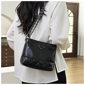 Close-up of a black leather bucket bag with quilted patterns and silver chain strap
