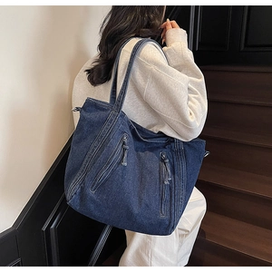 Detail of a large capacity denim tote bag with dual front zippers and retro navy blue finish