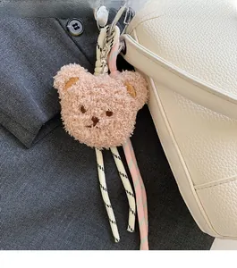 Détail d'un charm ours en peluche attaché à un sac à main en cuir blanc
