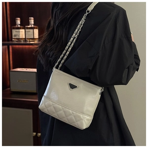 Detail of cream quilted leather crossbody bag with chain strap and triangular metal plaque