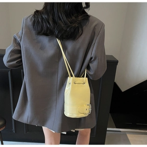 Détail du sac seau jaune vif avec fermeture à cordon et boucle décorative en bas